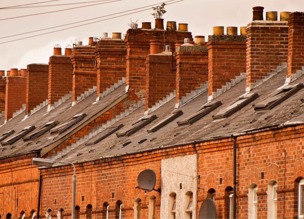Row of red brick terraced houses with many chimneys.